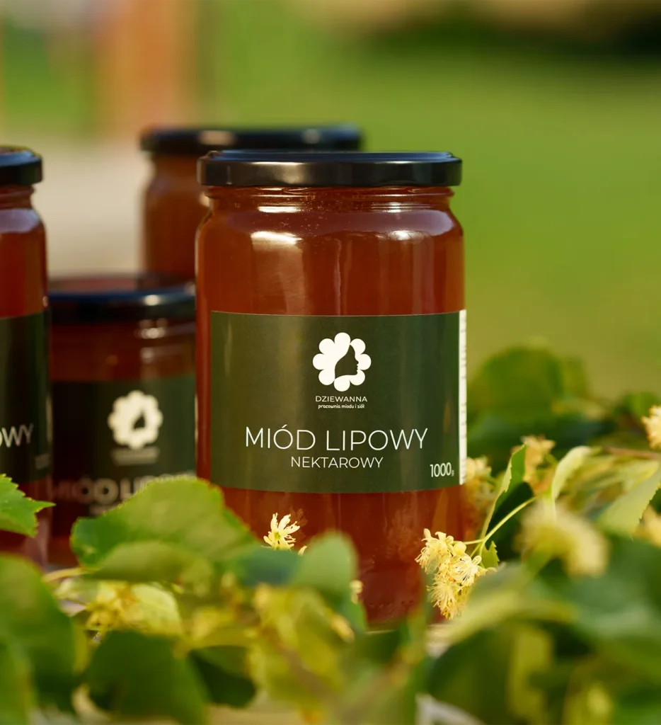 Miód lipowy od Dziewanny wśród zielonych liści i kwiatów lipy